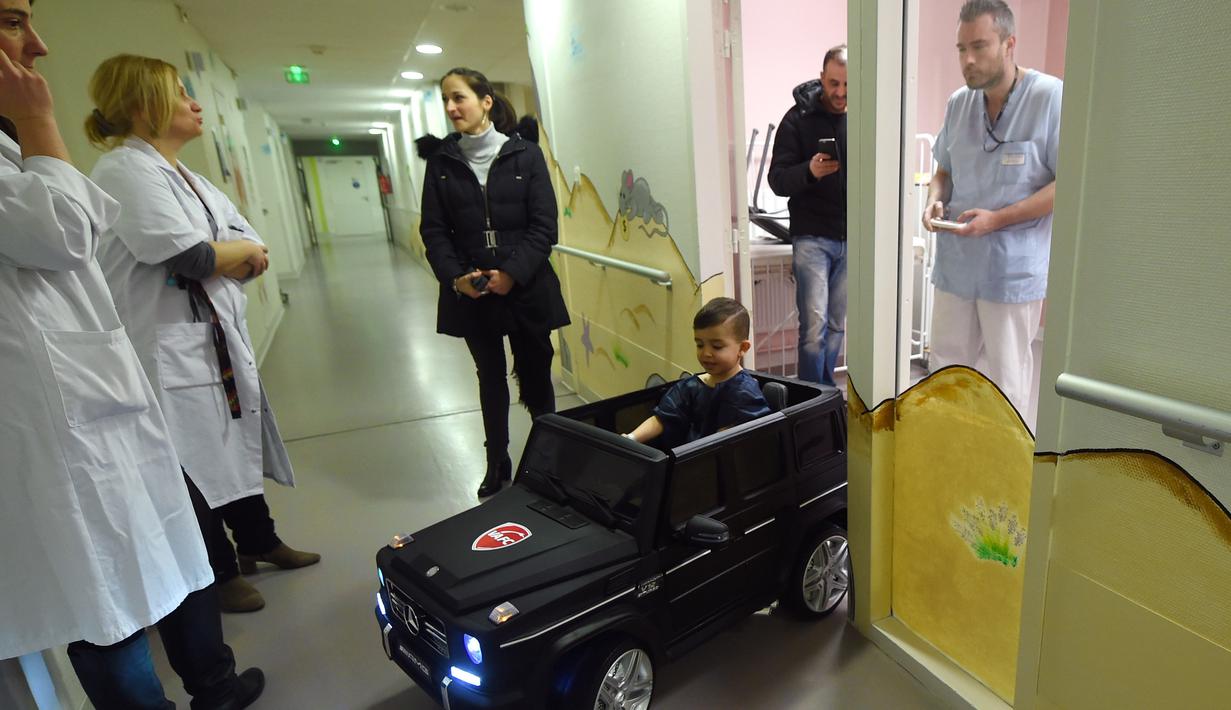 Souvail (2) mengendarai mobil mainan listrik menuju ruang operasi di Rumah Sakit Valenciennes, Prancis, Jumat (2/2). Rumah sakit ini memiliki tiga mobil mainan yang salah satunya sumbangan dari Valenciennes Football Club. (FRANCOIS LO PRESTI/AFP)