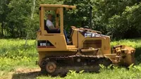 Vin Diesel sedang belajar mengendarai traktor Caterpillar di sebuah lahan peternakan di Eropa.