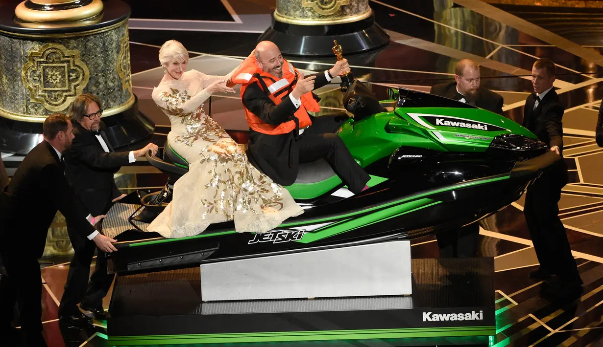 Helen Mirren duduk dibelakang Mark Bridges yang mengendarai jet ski dalam acara Academy Awards ke-90 di Hollywood, California (4/3). Mark Bridges berpidato hanya 36 detik saat meraih kategori Desain Kostum Terbaik. (Chris Pizzello / Invision / AP)