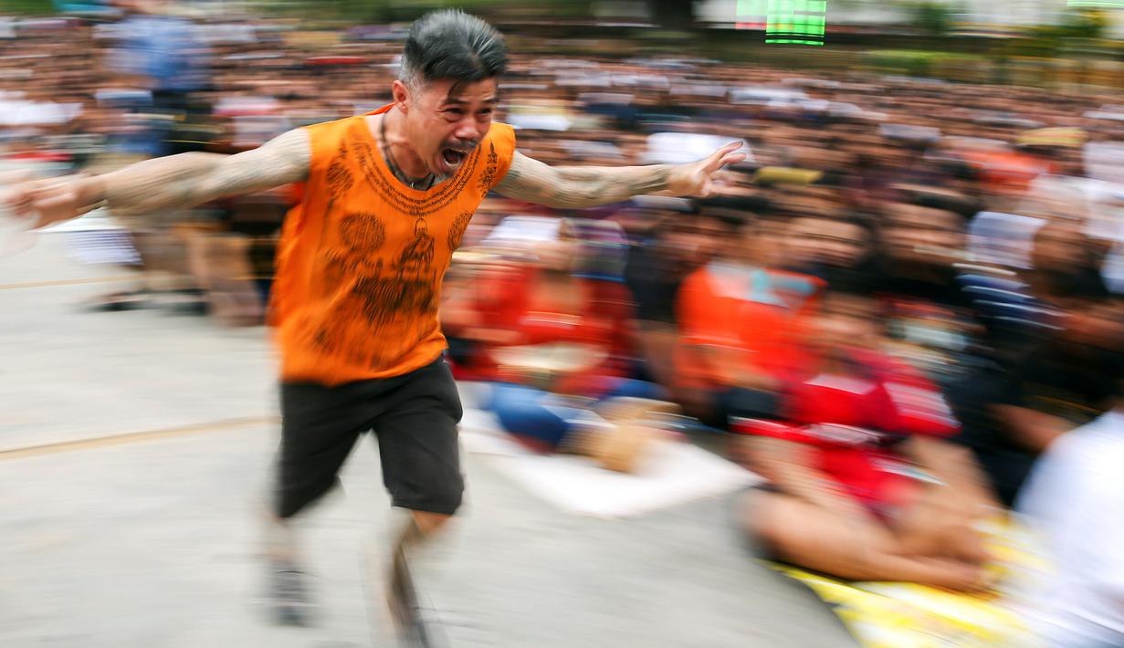 Pria bertato berlari saat kesurupan selama Festival Tato Suci di kuil Wat Bang Phra, Nakhon Pathom, Thailand (16/3). Mereka percaya tato memiliki kekuatan mistis, menangkal nasib buruk dan melindungi mereka dari bahaya. (Reuters/Athit Perawongmetha)
