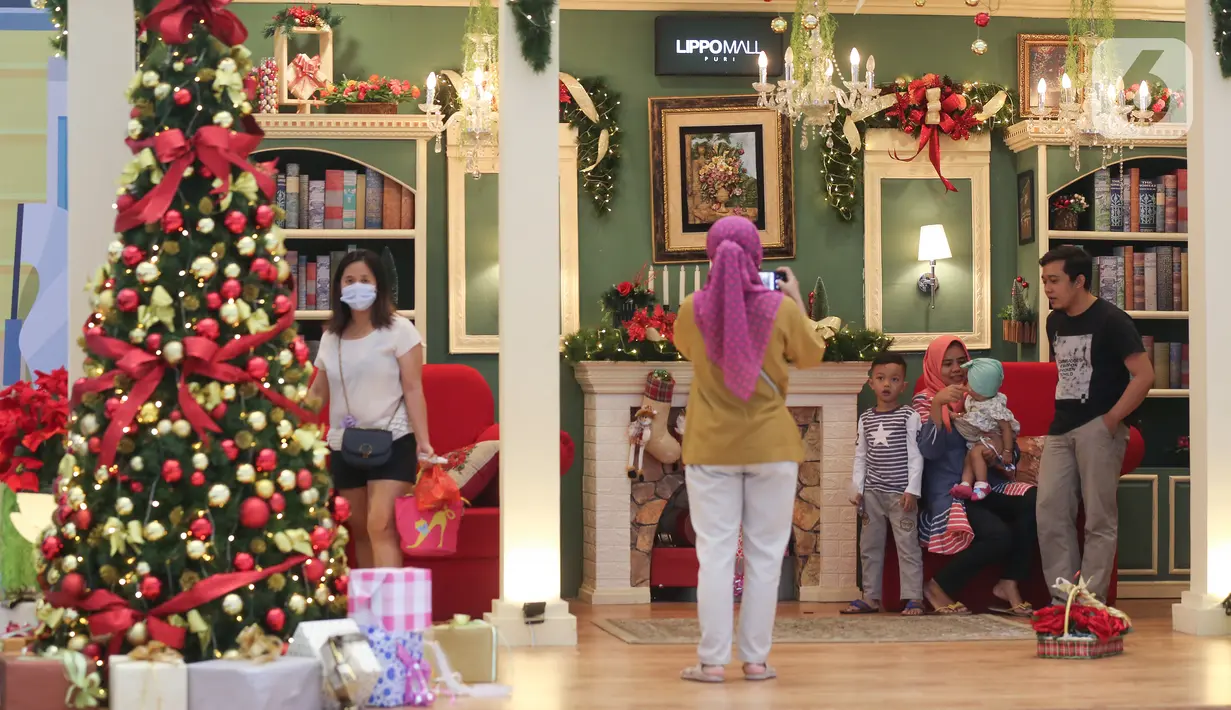 Pengunjung berfoto bersama keluarga dengan dekorasi Natal di atrium Lippo Mall Puri, Jakarta Barat, Sabtu (19/12/2020). Dominasi warna merah dan pohon cemara berhias lampu meriahkan sambut Hari Raya Natal dan Tahun Baru di atrium 1 dan 2. (Liputan6.com/Fery Pradolo)