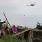 Sejumlah warga saat santai sembari menyaksikan helikopter waterboombing yang melakukan pemadaman di lokasi karhutla gambut di Dusun Puding, Kecamatan Kumpeh, Kabupaten Muarojambi, Kamis (3/10/2019). (Liputan6.com/Gresi Plasmanto)