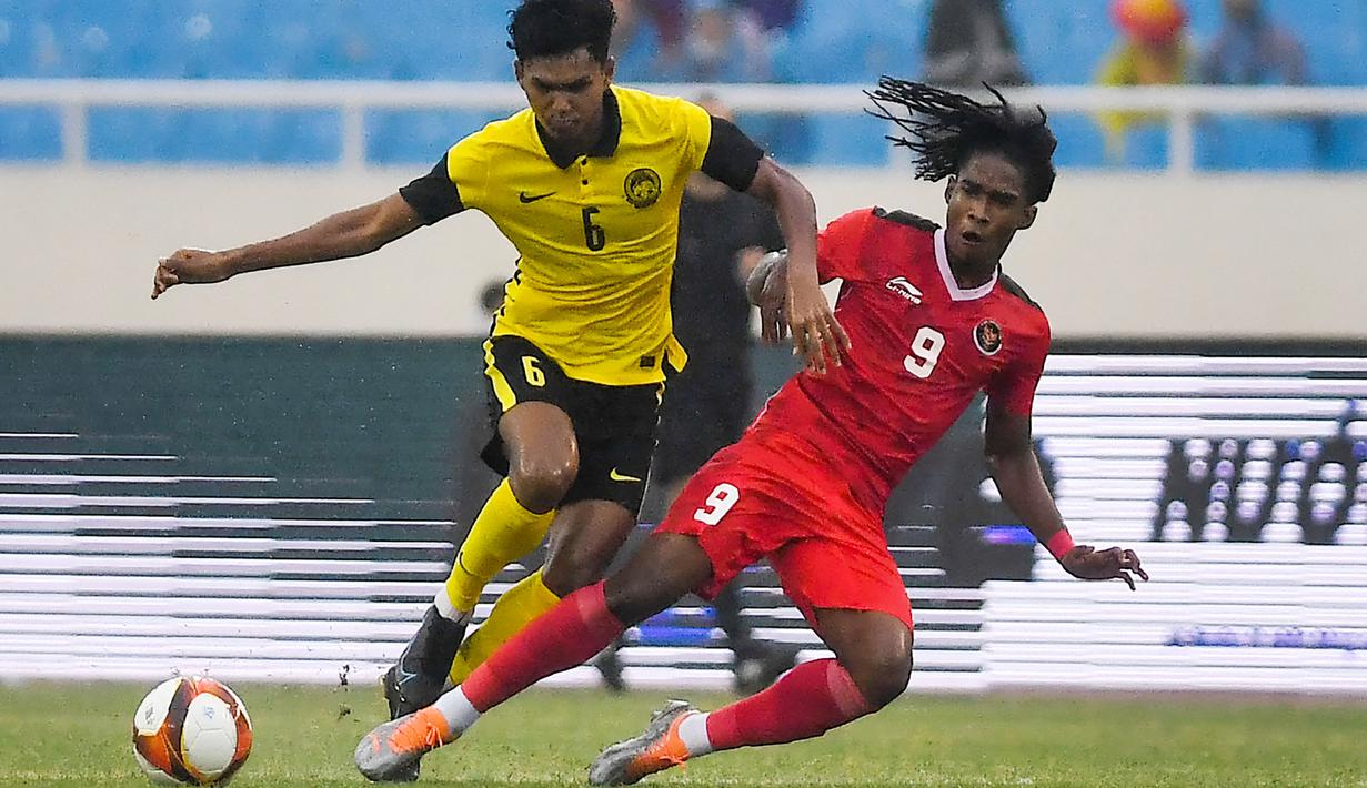 Pemain Timnas Indonesia, Ronaldo Kwateh, berebut bola dengan pemain Malaysia, Muhammad Azam, pada laga perebutan medali perunggu SEA Games 2021 yang digelar di Stadion My Dinh, Hanoi, Minggu (22/5/2022). (AFP/ Ye Aung Thu)
