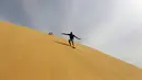Sejumlah pengunjung berseluncur menggunakan papan sandboards di gurun pasir Wadi el-Rayan Fayoum, Mesir (18/11). Sandboarding ini hampir sama dengan snowboarding, yang membedakan adalah medannya di atas pasir. (Reuters/Mohamed Abd El Ghany)