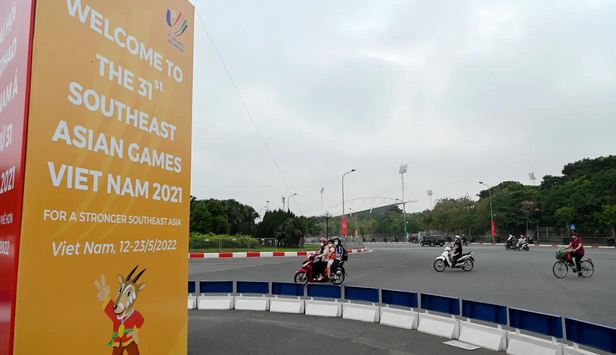<p>Pengendara mobil melewati tanda untuk Pesta Olahraga Asia Tenggara (Southeast Asian Games) atau biasa disingkat SEA Games ke-31, sehari sebelum upacara pembukaan di Hanoi, Vietnam, Rabu (11/5/2022). SEA Games 2021 akan dibuka pada 12 Mei 2022 di Stadion My Dinh dengan mempertandingkan 40 cabang olahraga (cabor) dalam 526 nomor. (TANG CHHIN Sothy / AFP)</p>