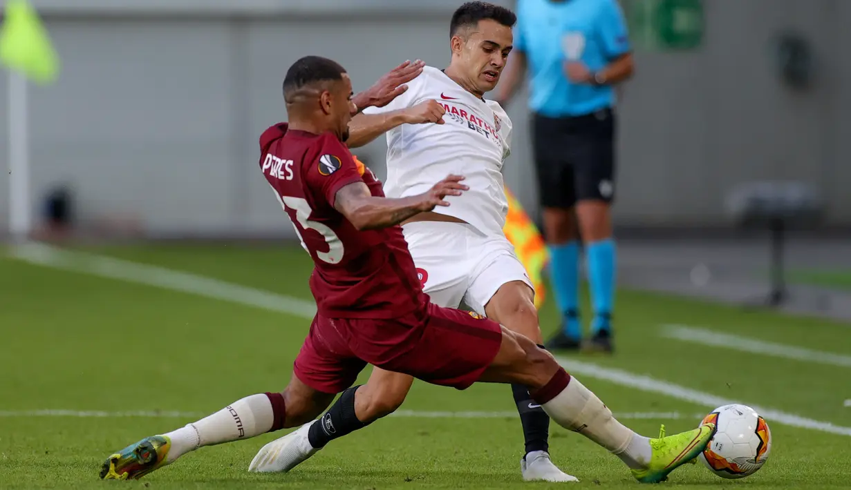 Pemain AS Roma, Bruno Peres berebut bola dengan bek Sevilla, Sergio Reguilon pada babak 16 besar Liga Europa di Stadion Schauinsland-Reisen-Arena, Kamis (6/8/2020). Sevilla lolos ke perempat final setelah mengandaskan AS Roma dengan skor 2-0. (Friedemann Vogel/Pool Photo via AP)