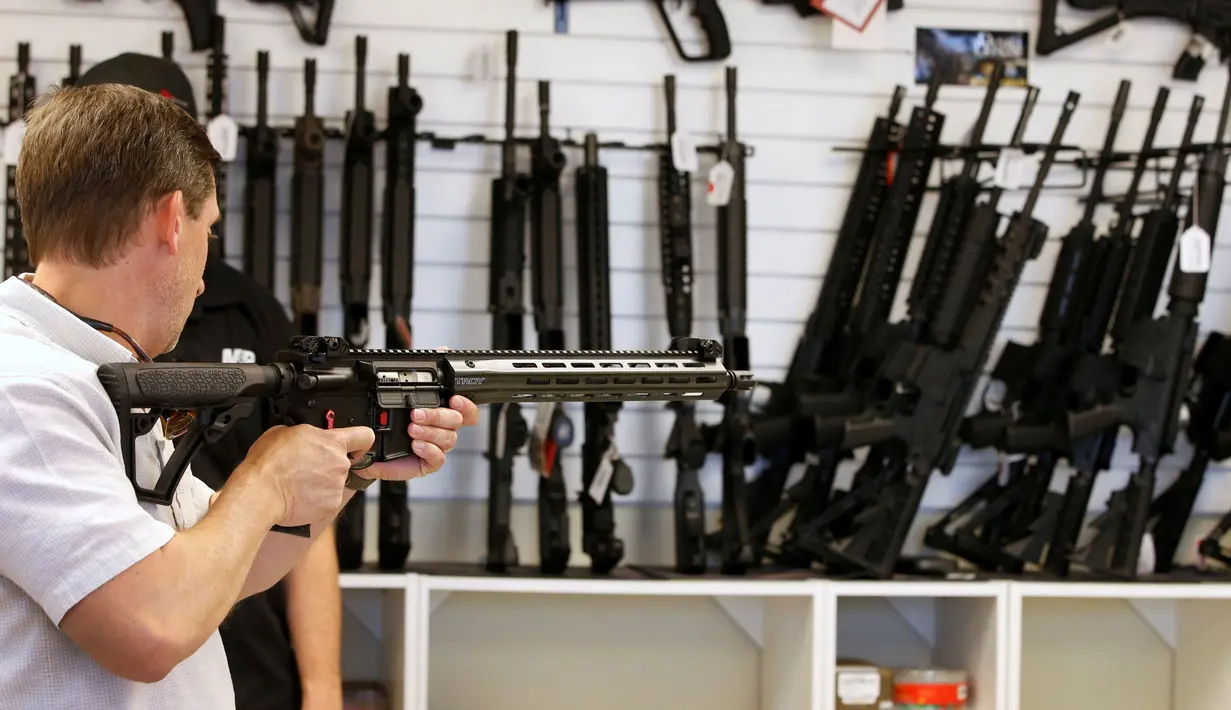 Calon pembeli saat memegang senapan serbu AR-15 di toko senjata "Ready Gunner", Utah, AS, (21/6). Peningkatan penjualan justru muncul ketika pemerintah membicarakan untuk melarang penjualan beberapa jenis senjata. (REUTERS/George Frey)
