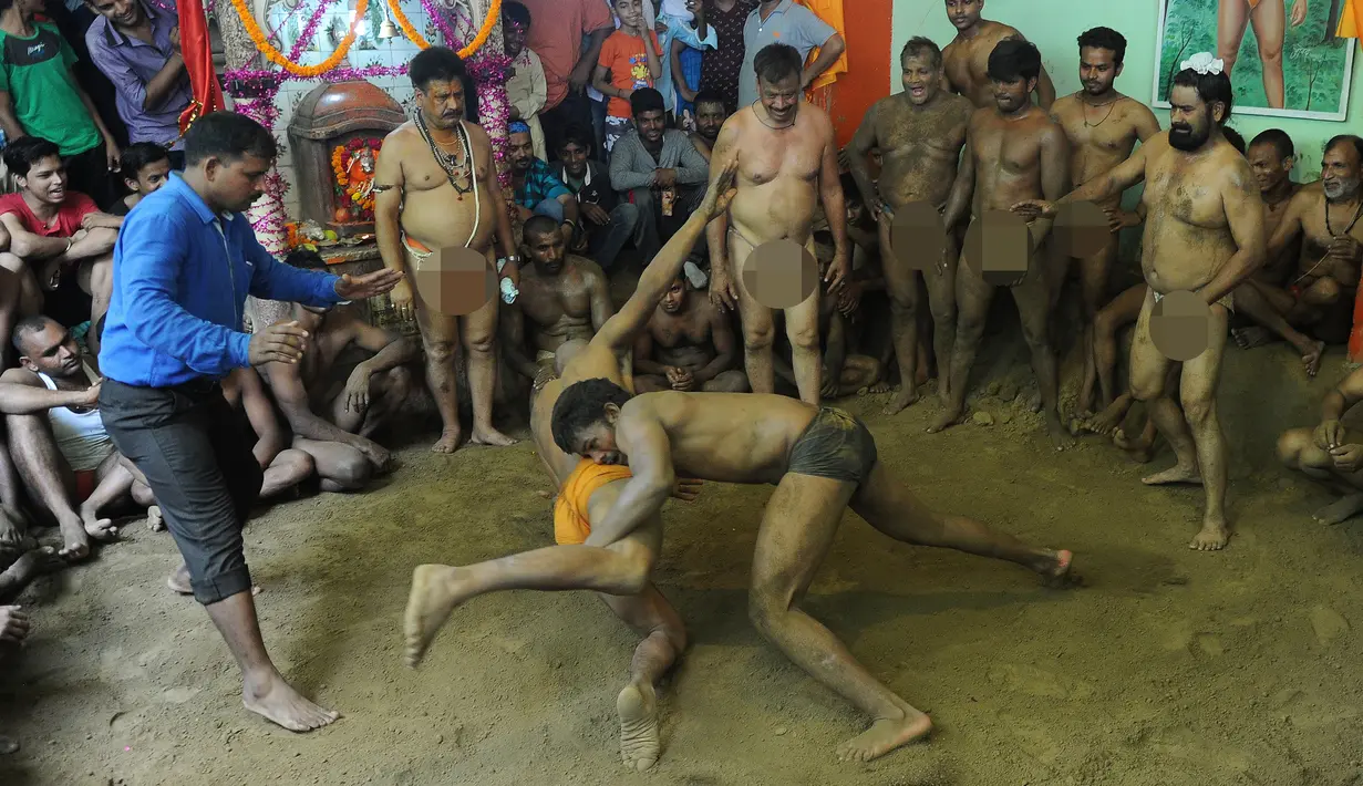 Seorang pegulat berusaha membanting lawannya pada pertandingan gulat tradisional di festival Nag Panchami di Allahabad, India, (7/8). Festival ini diadakan selama musim hujan dengan doa dan upeti untuk ular. (AFP PHOTO/SANJAY Kanojia)