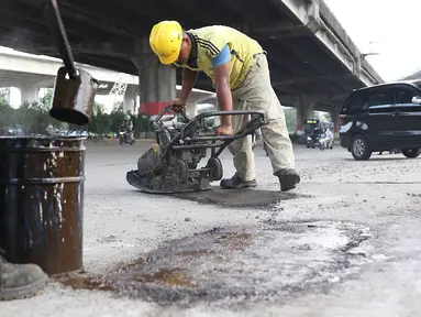 Petugas menambal lubang pada jalan yang rusak di kawasan Jatinegara, Jakarta, Kamis (7/2). Musim hujan yang mengguyur Jakarta selama beberapa waktu terakhir meninggalkan kerusakan pada sejumlah ruas jalan di Ibukota. (Liputan6.com/Immanuel Antonius)