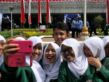 Sejumlah pelajar ber-selfi seusai mengikuti upacara memperingati Hari Pendidikan Nasional di Jakarta, Sabtu (2/5/2015). Peringatan tersebut mengangkat tema 'Gerakan Pencerdasan dan Penumbuhan Generasi Berkarakter Pancasila'. (Liputan6.com/Johan Tallo)