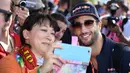 Pembalap Red Bull, Daniel Ricciardo melakukan selfie dengan seorang penggemar menjelang sesi latihan bebas pertama di Grand Prix Australia, Melbourne, Jumat (24/3). (AFP Photo/WILLIAM WEST)