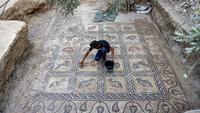Putra petani Palestina Salman al-Nabahin membersihkan mosaik era Bizantium yang ditemukan di Bureij, Jalur Gaza, Palestina, 18 September 2022. "Ini adalah lantai mosaik terindah yang ditemukan di Gaza, baik dari segi kualitas representasi grafis maupun kompleksitas geometrinya," kata Arkeolog René Elter. (MOHAMMED ABED/AFP)