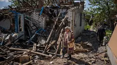 Sepasang penduduk membawa barang bawaan dari rumah mereka yang hancur di tengah invasi Rusia ke Ukraina, di desa Vilkhivka, dekat kota timur Kharkiv, pada 14 Mei 2022. Puluhan rumah di Vilkhivka, sebuah desa berpenduduk sekitar 2.000 jiwa, hancur oleh peluru, ledakan atau kebakaran. Puing-puing berserakan di jalan-jalan termasuk selongsong peluru, dan sisa-sisa amunisi. (Dimitar DILKOFF / AFP)