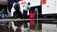 Seorang kenek bus membantu penumpang memasukkan koper ke dalam bagasi, Jakarta, (24/7/14) (Liputan6.com/ Johan Tallo) 