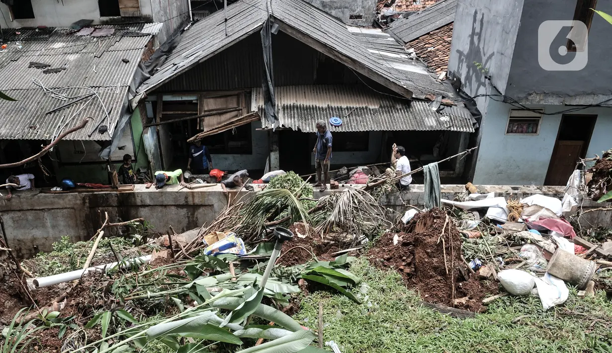 Warga membersihkan puing reruntuhan bangunan pascatanah longsor di kawasan Kemang Timur XI, Jakarta Selatan, Minggu (21/2/2021). Longsor terjadi akibat derasnya arus kali yang kemudian bangunan menimpa permukiman warga di bawahnya. (merdeka.com/Iqbal S. Nugroho)