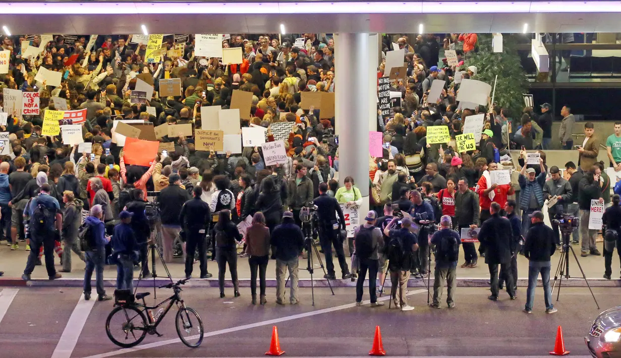 Ratusan massa berkumpul di Terminal Internasional Tom Bradley, Bandara LAX menggelar aksi protes, di Los Angeles, Sabtu (28/1). Mereka mengecam kebijakan Donald Trump yang melarang warga dari 7 negara mayoritas muslim, masuk ke AS. (AP Photo/Reed Saxon)