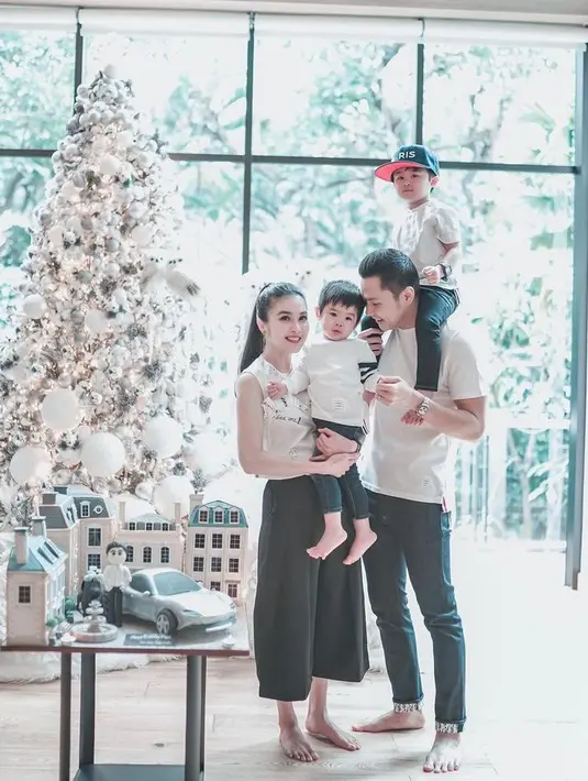 Sandra Dewi juga turut merayakan momen Natal dengan mengenakan busana nuansa putih yang serasi dengan ornamen pohon natal mereka. (Instagram/sandradewi88).