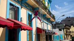 Seorang pria mengecat bagian balkon di Havana, Kuba (28/12). Kota ini terletak sekitar 144 kilometer di selatan-barat daya dari Key West, Florida.  (AP Photo / Desmond Boylan)