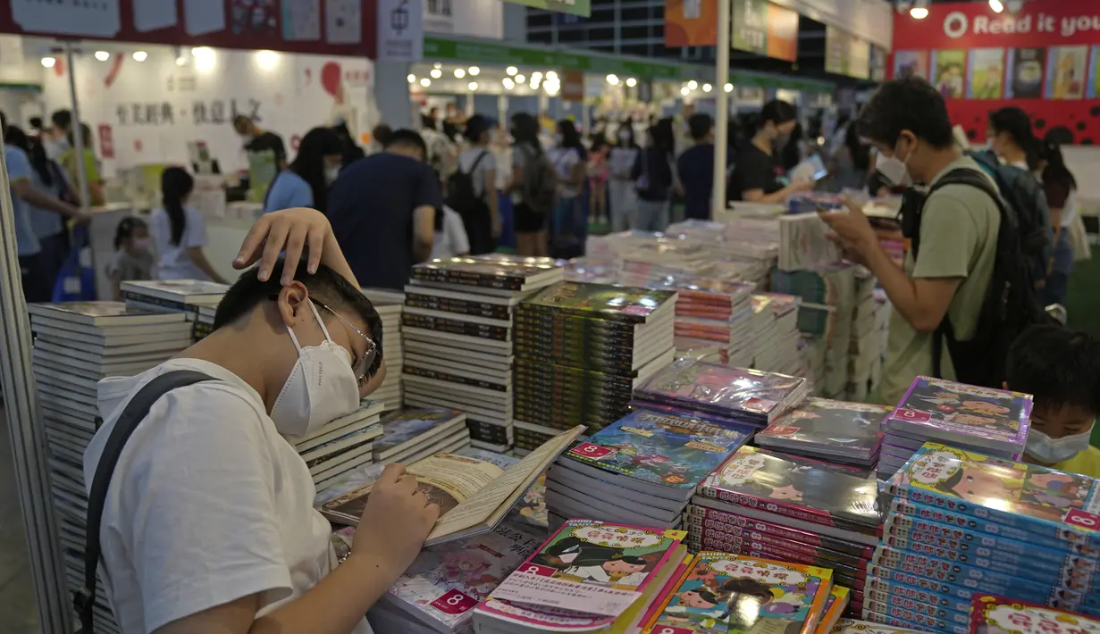 Pengunjung membaca di stan selama pameran buku tahunan di Hong Kong, Rabu (20/7/2022). Pameran Buku Hong Kong akan diadakan pada 20-26 Juli. (AP Photo/Kin Cheung)