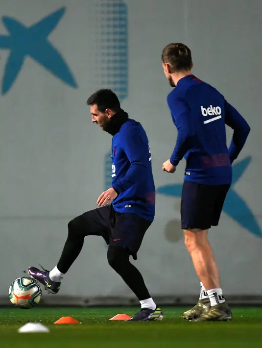 Penyerang Barcelona, Lionel Messi (kiri) mengontrol bola saat mengikuti sesi latihan tim di Joan Gamper Sports City di Sant Joan Despi (17/12/2019). Barcelona akan bertanding melawan Real Madrid dalam laga El Clasico di Camp Nou. (AFP/Lluis Gene)