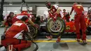 Mekanik Ferrari menganti ban jelang ajang sesi latihan Grand Prix Singapura F1 (18/9/2015). Kabut asap yang menyelimuti sirkuit tak menyurutkan pembalap untuk tetap melakukan pemanasan. (REUTERS/Olivia Harris)