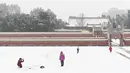 Orang-orang bermain ketika salju turun di sebuah taman di Beijing (16/12/2019). Beijing telah mengeluarkan peringatan untuk jalan-jalan es dan menyarankan warga untuk waspada terhadap gangguan lalu lintas, masalah kesehatan dan cuaca berangin setelah salju. (AFP Photo/Wang Zhao)