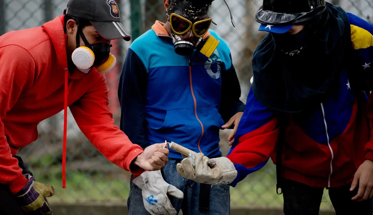 Tiga mahsiswa menyalakan petasan selama bentrokan dengan pasukan keamanan selama protes menuntut peningkatan anggaran beasiswa dan membuka kembali kafetaria universitas di Caracas, Venezuela (21/11). (AP Photo/Ariana Cubillos)