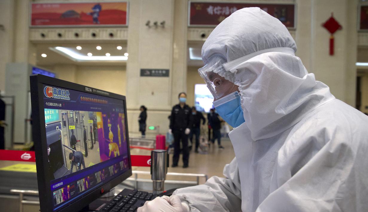 Petugas mengenakan alat pelindung diri saat memonitor pemindai suhu di Stasiun Hankou, Wuhan, Provinsi Hubei, China, Rabu (8/4/2020). Setelah 11 minggu lockdown, layanan kereta di kota yang menjadi titik awal pandemi virus corona COVID-19 ini kembali beroperasi. (AP Photo/Ng Han Guan)