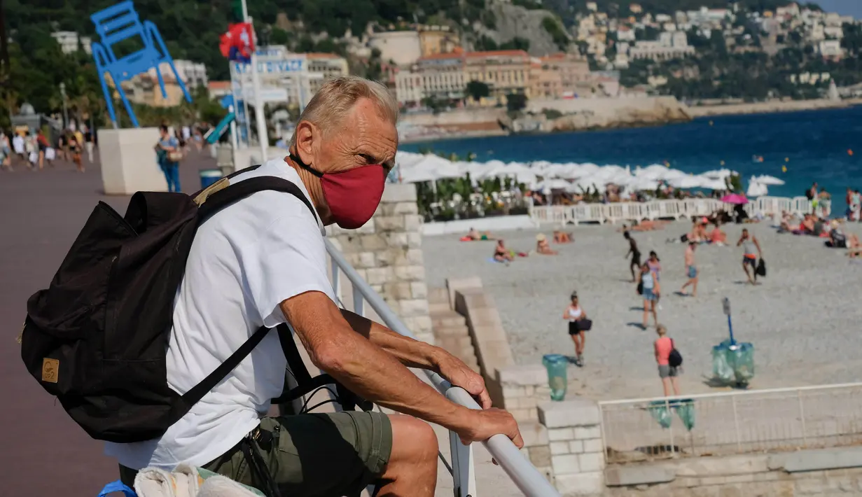 Seorang pria yang memakai masker mengunjungi sebuah pantai yang ada di Nice, Prancis selatan, pada Rabu (22/7/2020). Banyak pengunjung memadati Nice selama liburan musim panas di tengah pandemi COVID-19. (Xinhua/Serge Haouzi)