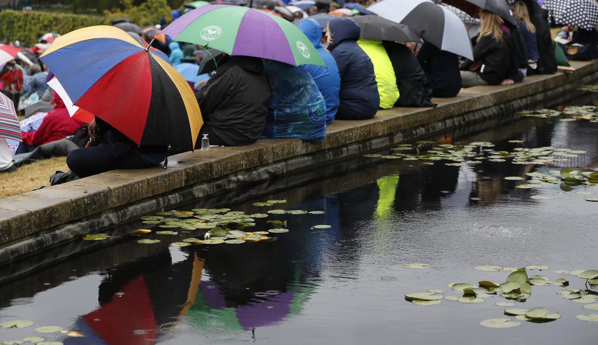 Deretan payung yang digunakan penonton saat menyaksikan tenis Wimblledon 2017 antara Johanna Konta melawan Simona Halep lewat layar di The All England Lawn Tennis Club, London, (11/7/2017). (AP/Kirsty Wigglesworth)