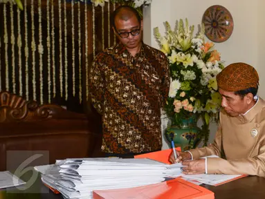 Presiden Jokowi (kanan) didampingi Sekretaris Kabinet Andi Widjajanto (kiri) menandatangani berkas-berkas saat berkantor di rumahnya di Jalan Kutai Utara RT.08/RW.07 Sumber, Solo, Jateng, Rabu (10/6/2015). (Liputan6.com/Faizal Fanani)