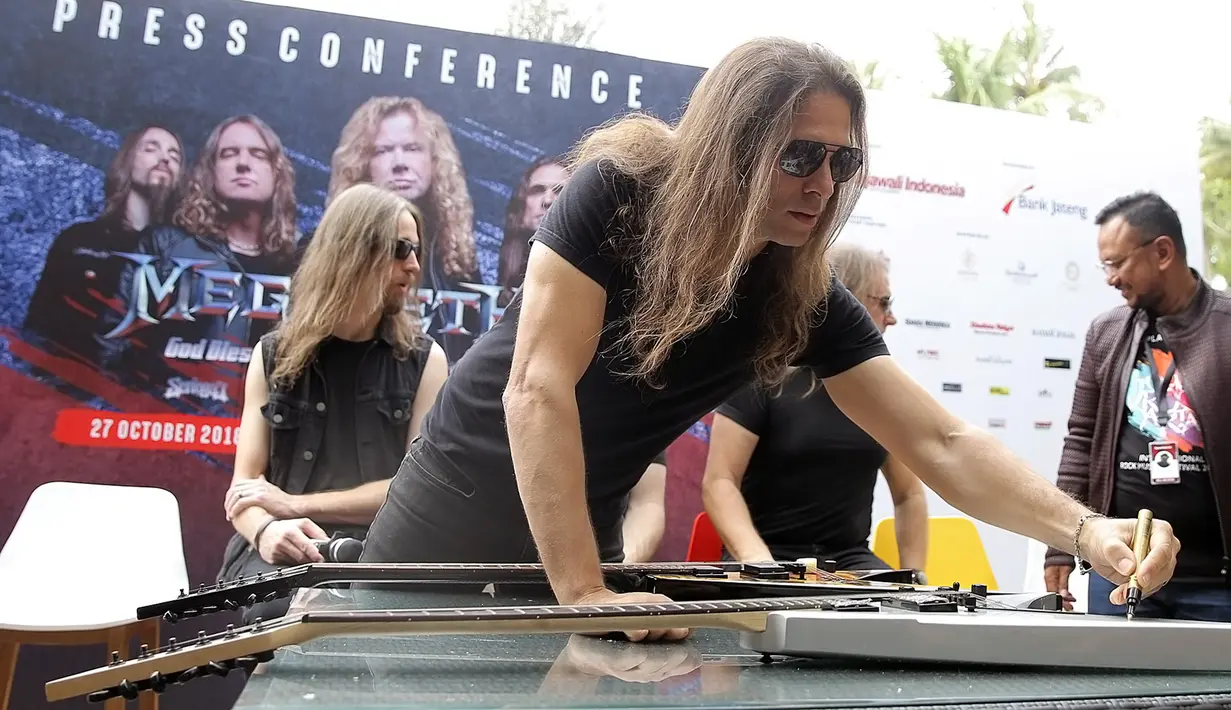 Gitaris Megadeth, Kiko Loureiro menandatangani gitar saat jumpa pers di Yogyakarta, Jumat (26/10). Kedatangan mereka dipromotori oleh Rajawali Indonesia Communication yang dipimpin oleh Anas Syahrul Alimi. (Liputan6.com/Bambang E.Ros)
