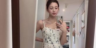 Lee Da In terlihat berfoto selfie mengenakan mini dress dengan motif floral. Mini dress putih bertali tipis ini memiliki detail motif mini floral yang cantik dengan sedikit ruffles di ujung gaun. Foto: Instagram.