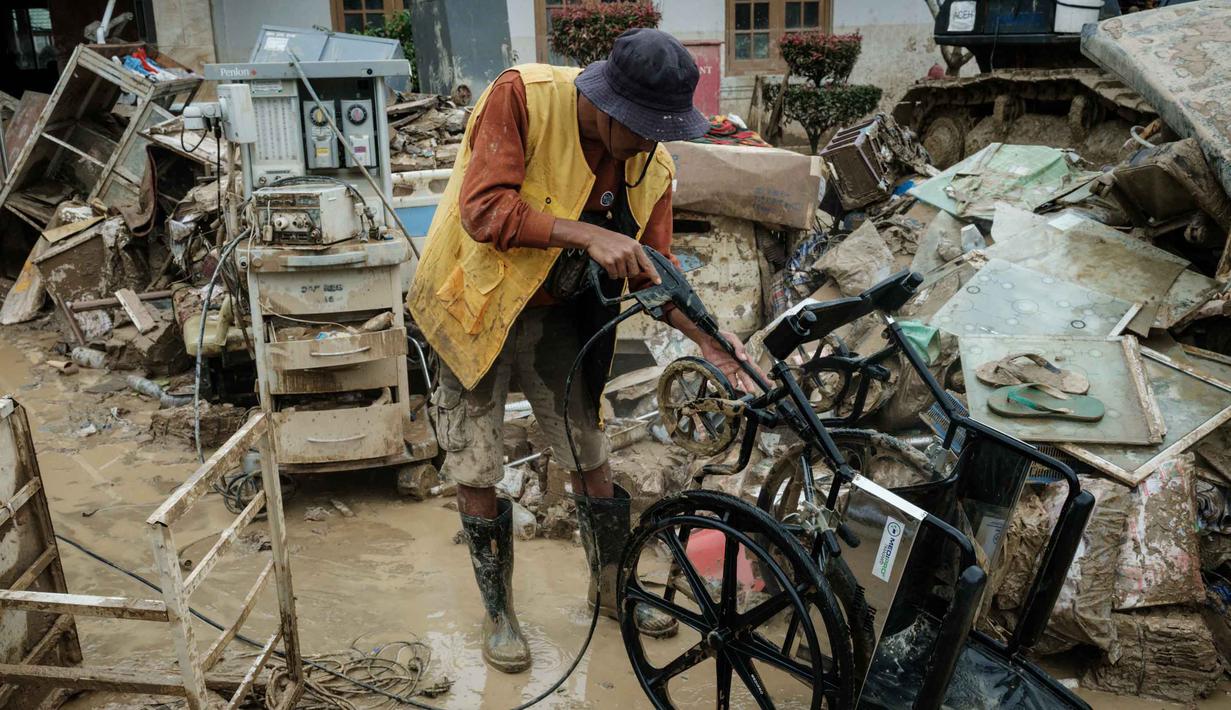 Pekerja dibantu personel Tentara Nasional Indonesia (TNI) dari YONIF TP 853/BRB, Aceh Timur, dan sejumlah relawan terus melakukan upaya pembersihan. Tampak dalam foto, seorang pekerja membersihkan peralatan medis yang terendam banjir bandang sekitar tiga bulan lalu di Rumah Sakit Daerah Aceh Tamiang, pada Selasa 16 Desember 2025.  (Yasuyoshi CHIBA/AFP)