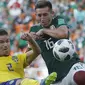 Pemain Swedia, Mikael Lustig (kiri) menghalau bola dari kejaran pemain Meksiko, Hector Herrera pada laga grup F Piala Dunia 2018 di Yekaterinburg Arena, Yekaterinburg, Rusia, (27/6/2018).  Swedia menang telak 3-0 atas Meksiko. (AP/Eduardo Verdugo)