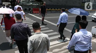 Pekerja melintasi pelican crossing di kawasan Jakarta, Senin (9/10/2023). (Liputan6.com/Angga Yuniar)