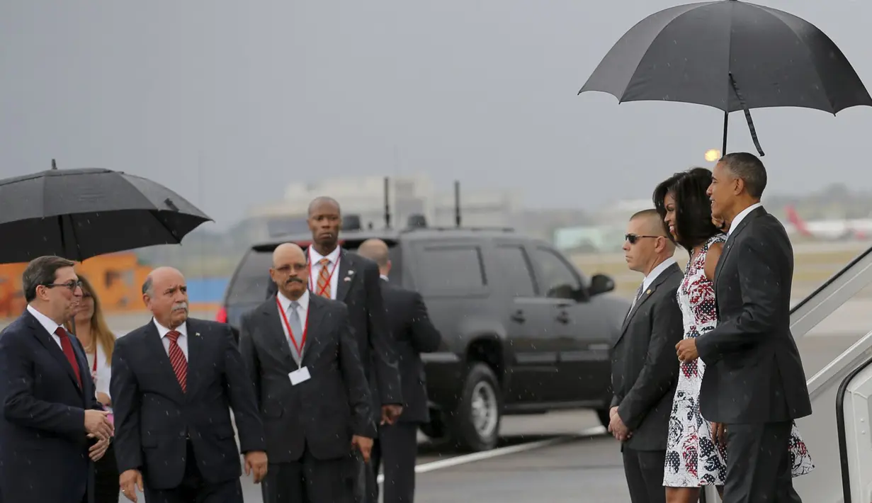 Presiden AS Barack Obama dan istrinya Michelle disambut Menlu Kuba, Bruno Rodriguez (kiri) setibanya di Bandara Internasional Havana, Minggu (20/3). Kunjungan Obama ini yang pertama dilakukan seorang presiden AS sejak 88 tahun lalu. (REUTERS/stringer)