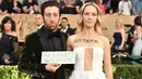 Aktor Simon Helberg dan istri, Jocelyn Towne menarik perhatian di karpet merah Screen Actors Guild (SAG) Awards di Los Angeles, Minggu (29/1). Bintang 'The Big Bang Theory' itu membawa papan bertuliskan 'Refugees Welcome'. (Jordan Strauss/Invision/AP)