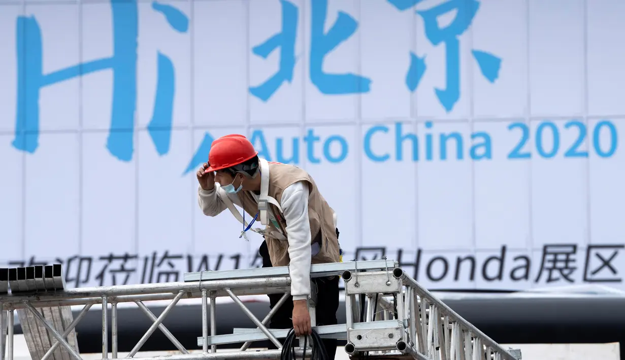 Seorang pekerja berada dekat papan bertuliskan "Hai Beijing, Auto China 2020" menjelang pameran Auto China 2020 yang akan digelar di Beijing, Kamis (24/9/2020). (AP Photo/Ng Han Guan)