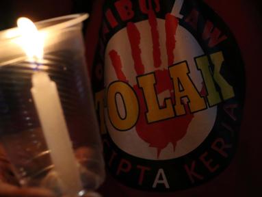Salah satu peserta aksi unjuk rasa memegang lilin saat doa bersama lintas agama di Kawasan Patung Kuda, Jakarta, Selasa (10/11/2020). Sejumlah massa gabungan dari berbagai organisasi buruh dan mahasiswa berunjuk rasa menolak pengesahan Omnibus Law UU Cipta Kerja. (Liputan6.com/Helmi Fithriansyah)