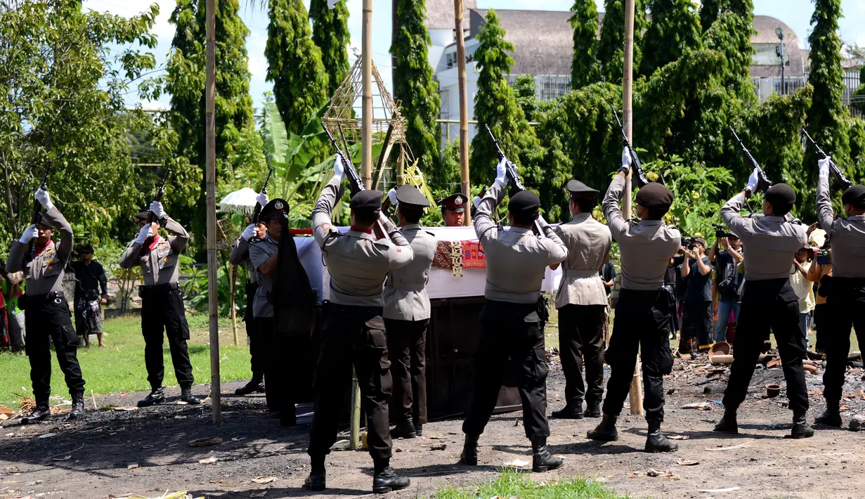 Petugas melepas tembakan salvo ke udara saat upacara pemakaman anggota Polsek Kuta, Aipda I Wayan Sudarsa di Jimbaran, Bali, Minggu (21/8). Prosesi secara institusi Polri itu dilakukan sebelum jenazah dibakar sesuai adat Hindu. (SONNY Tumbelaka/AFP)