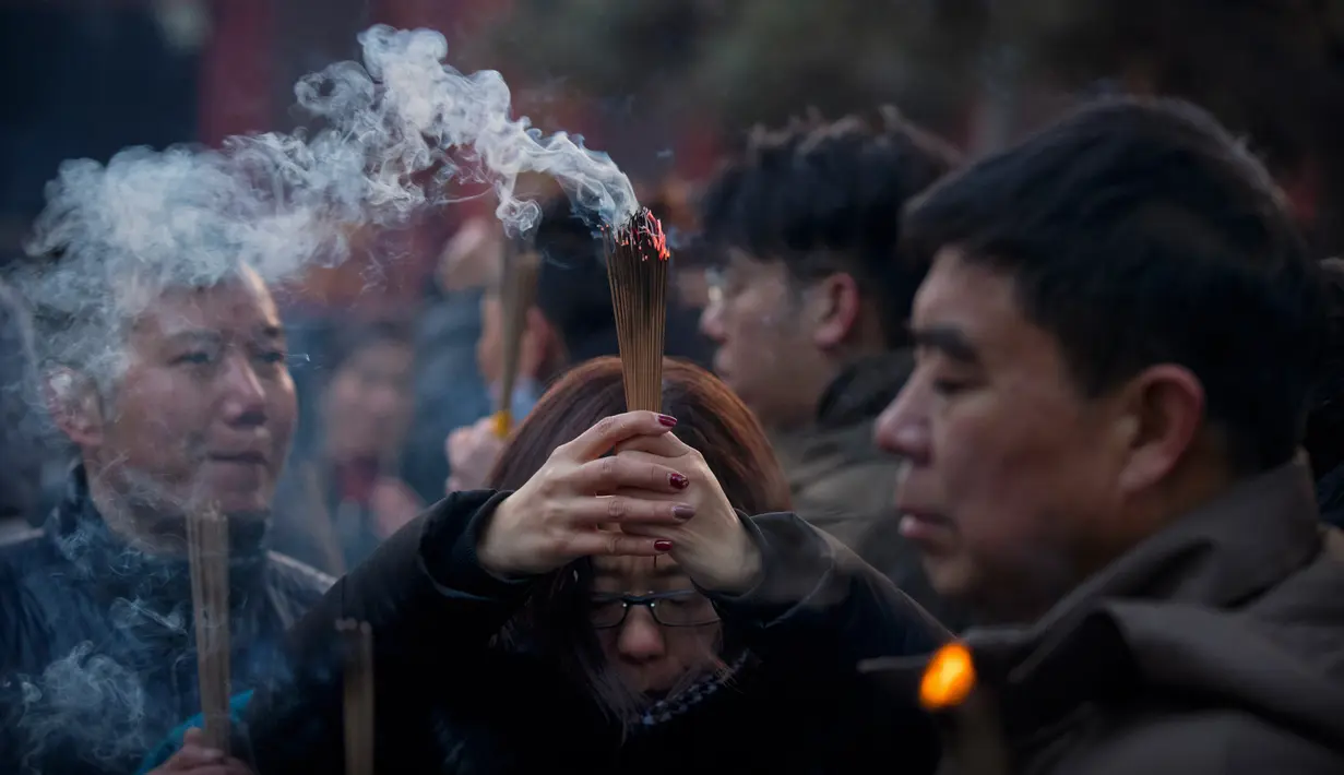 Seorang wanita memegang dupa berdoa di Kuil Lama di Beijing (5/2). Orang-orang China merayakan hari pertama Tahun Baru Imlek pada hari Selasa, Tahun Babi di zodiak Tiongkok dengan berdoa di kuil. (AP Photo/Mark Schiefelbein)
