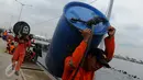 Petugas Basarnas membawa drum kosong untuk mengangkat bangkai kapal Zahro Express di Pelabuhan Muara Angke, Jakarta, Rabu (4/1). Puluhan drum kosong dipasang di sekeliling bangkai kapal untuk mengangkat kapal perlahan-lahan. (Liputan6.com/Gempur M Surya)