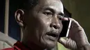 Bapak Sumarti Ningsih, Ahmad Kaliman berbincang lewat ponsel mengenai sidang pembunuhan anaknya di Cilacap, Jawa Tengah , Indonesia (8/11). Rurik Jutting telah dinyatakan dijatuhi hukuman penjara seumur hidup. (REUTERS/Idhad Zakaria)
