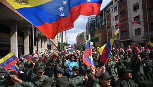 Penangkapan dilakukan atas perintah Presiden Amerika Serikat, Donald Trump, terkait tuduhan narkoterorisme, perdagangan narkoba internasional, dan penyelundupan kokain. Tampak dalam foto, seorang wanita mengibarkan bendera Venezuela di antara anggota Angkatan Bersenjata Bolivarian Nasional selama demonstrasi dukungan untuk mantan Presiden Venezuela Nicolas Maduro dan istrinya Cilia Flores di Caracas pada 6 Januari 2026. (Federico PARRA/AFP)