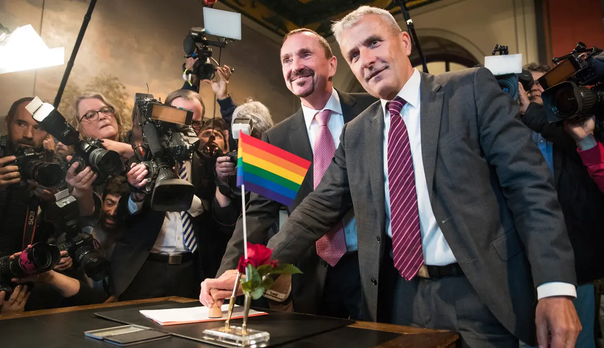 Pasangan gay, Bode Mende (kanan) dan Karl Kreile (kiri) menuliskan akta nikah mereka saat upacara pernikahannya di balai kota Schoeneberg di Berlin, Jerman (1/10). (AFP Photo/Odd Andersen)