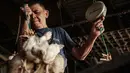 Seorang pria membawa ayam untuk ditimbang sebelum pengiriman di sebuah peternakan unggas, Jakarta pada 4 April 2026. Harga sejumlah komoditas pangan masih menunjukkan tren tinggi. (YASUYOSHI CHIBA/AFP)