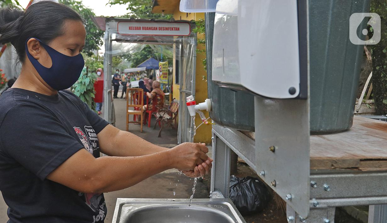 Calon pembeli mencuci tangan sebelum berbelanja di pedagang sayur keliling di Taman Anyelir 3, Depok, Selasa (28/4/2020). Warga Taman Anyelir 3 menerapkan pembatasan jarak fisik agar tidak terjadi penumpukan pelanggan sebagai upaya pencegahan penyebaran Covid-19. (Liputan6.com/Herman Zakharia)