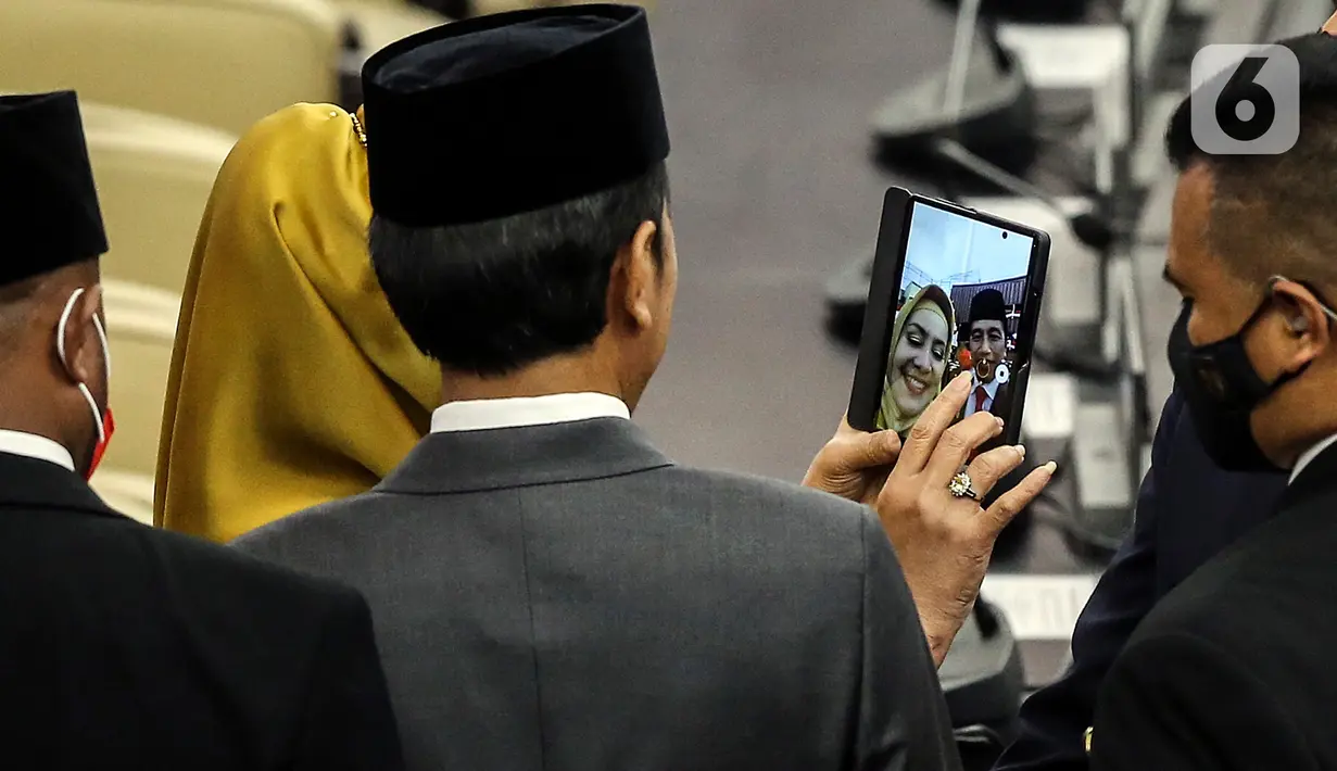 Seorang anggota DPR berswafoto dengan Presiden Joko Widodo pada rapat Paripurna DPR pembukaan masa persidangan I DPR tahun sidang 2022-2023 di Gedung Nusantara, Kompleks Parlemen, Senayan, Jakarta, Selasa (16/8/2022). (Liputan6.com/Johan Tallo)
