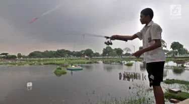 Seorang anak memancing di area banjir yang merendam TPU Semper, Jakarta, Selasa (4/12). TPU Semper menjadi langganan banjir saat musim penghujan akibat rendahnya permukaan tanah dengan ketinggian air sepinggang orang dewasa. (Merdeka.com/Iqbal S. Nugroho)